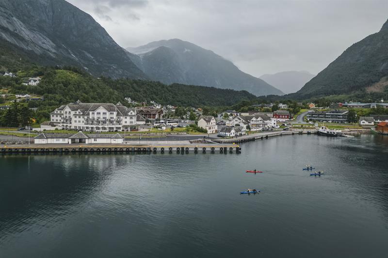 Four kayaks paddling past the Vøringfoss Hotel and the cruiseport.