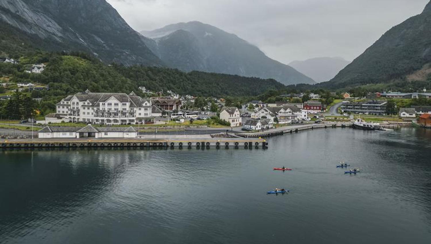Four kayaks paddling past the Vøringfoss Hotel and the cruiseport.