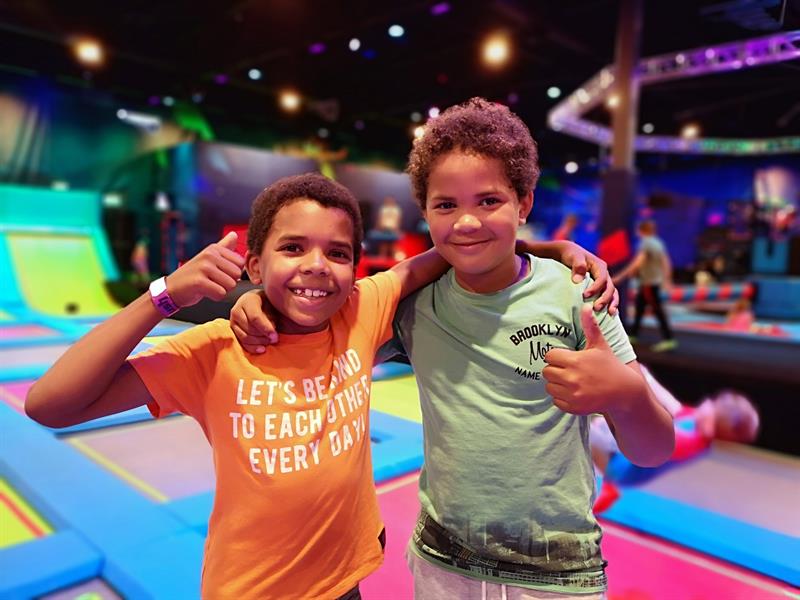 Two boys giving thumbs up to camera.