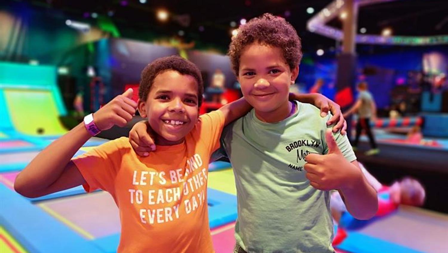 Two boys giving thumbs up to camera.