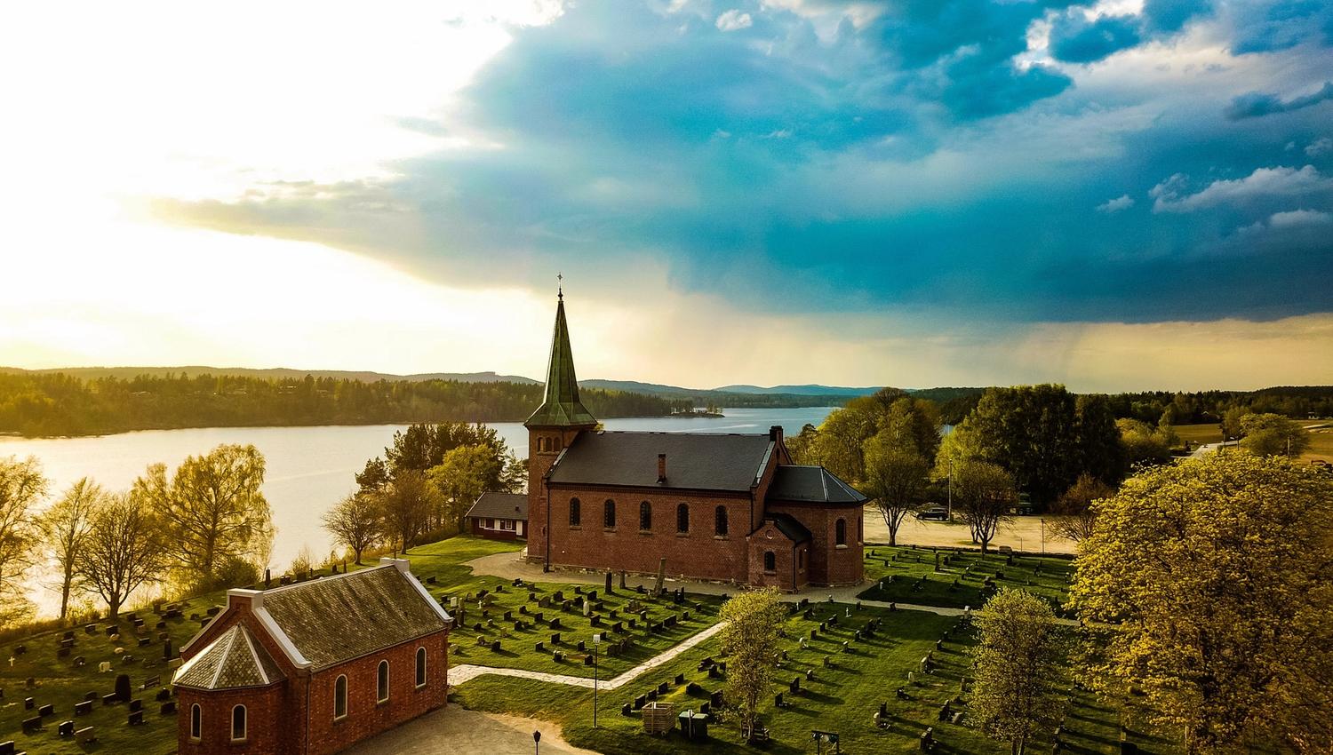 Aremark kirke, fotografert med drone og med utsikt til Aremarksjøen. Foto:Martin Myrene