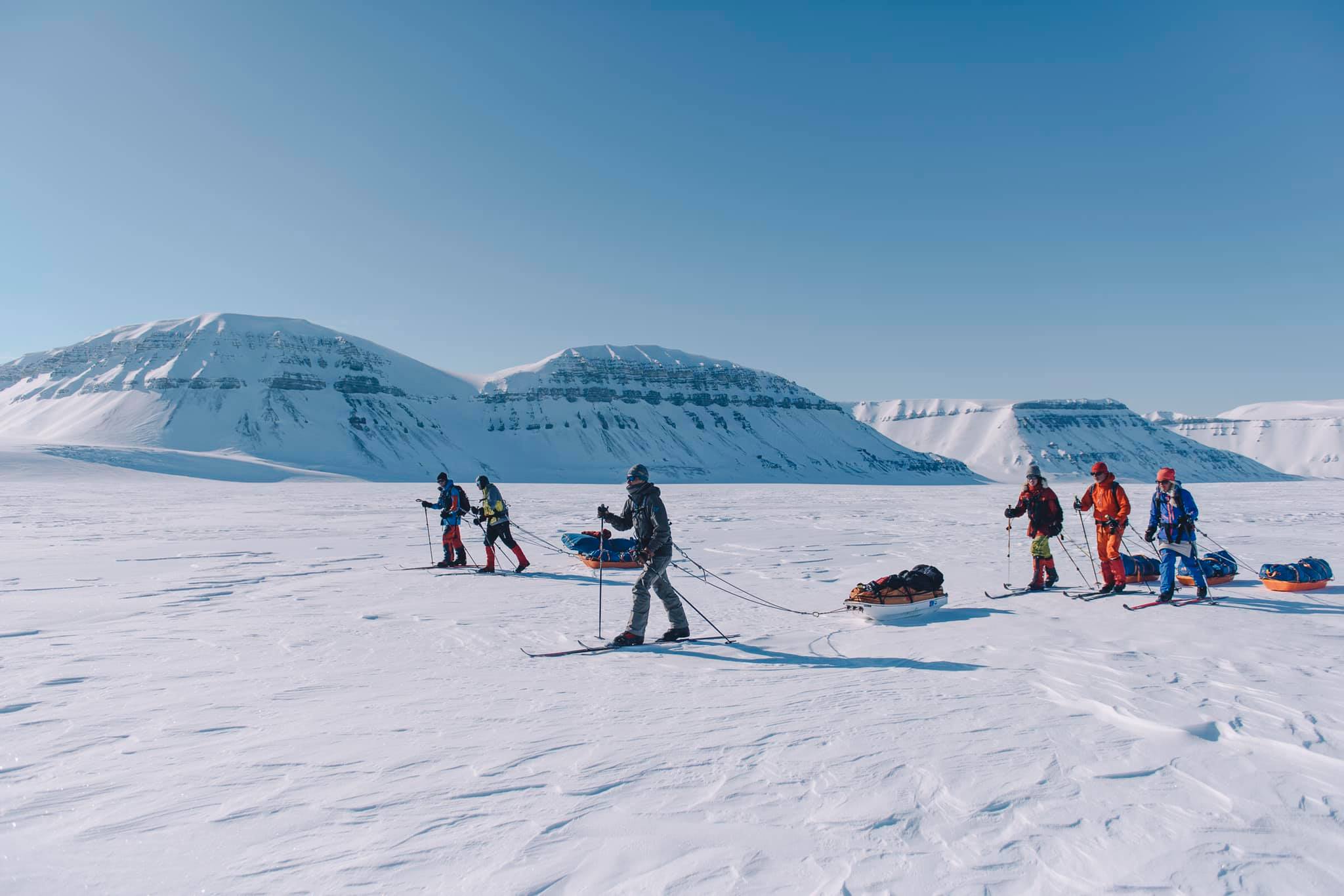A tour group of skiers pulling sleds