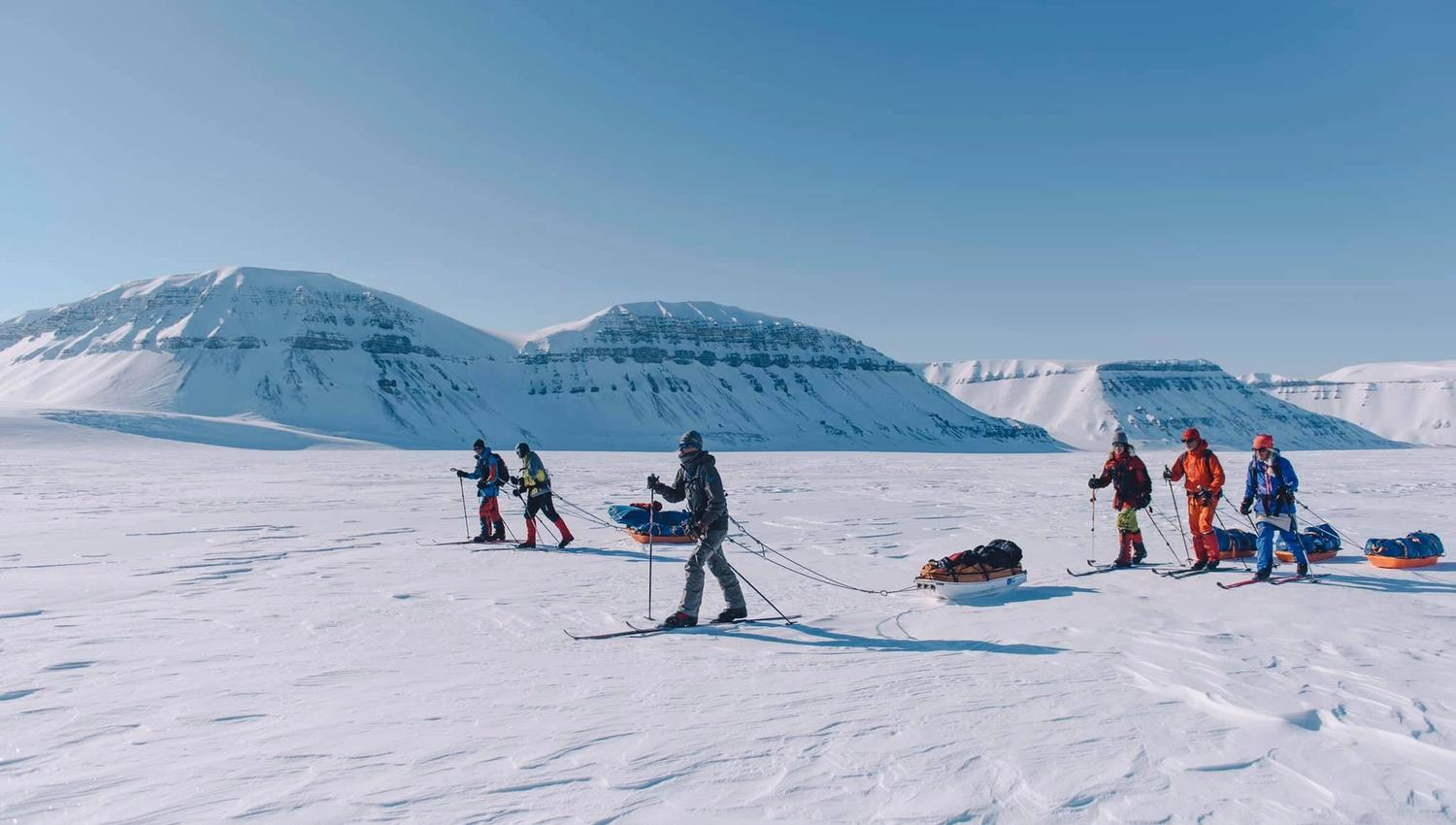 A tour group of skiers pulling sleds