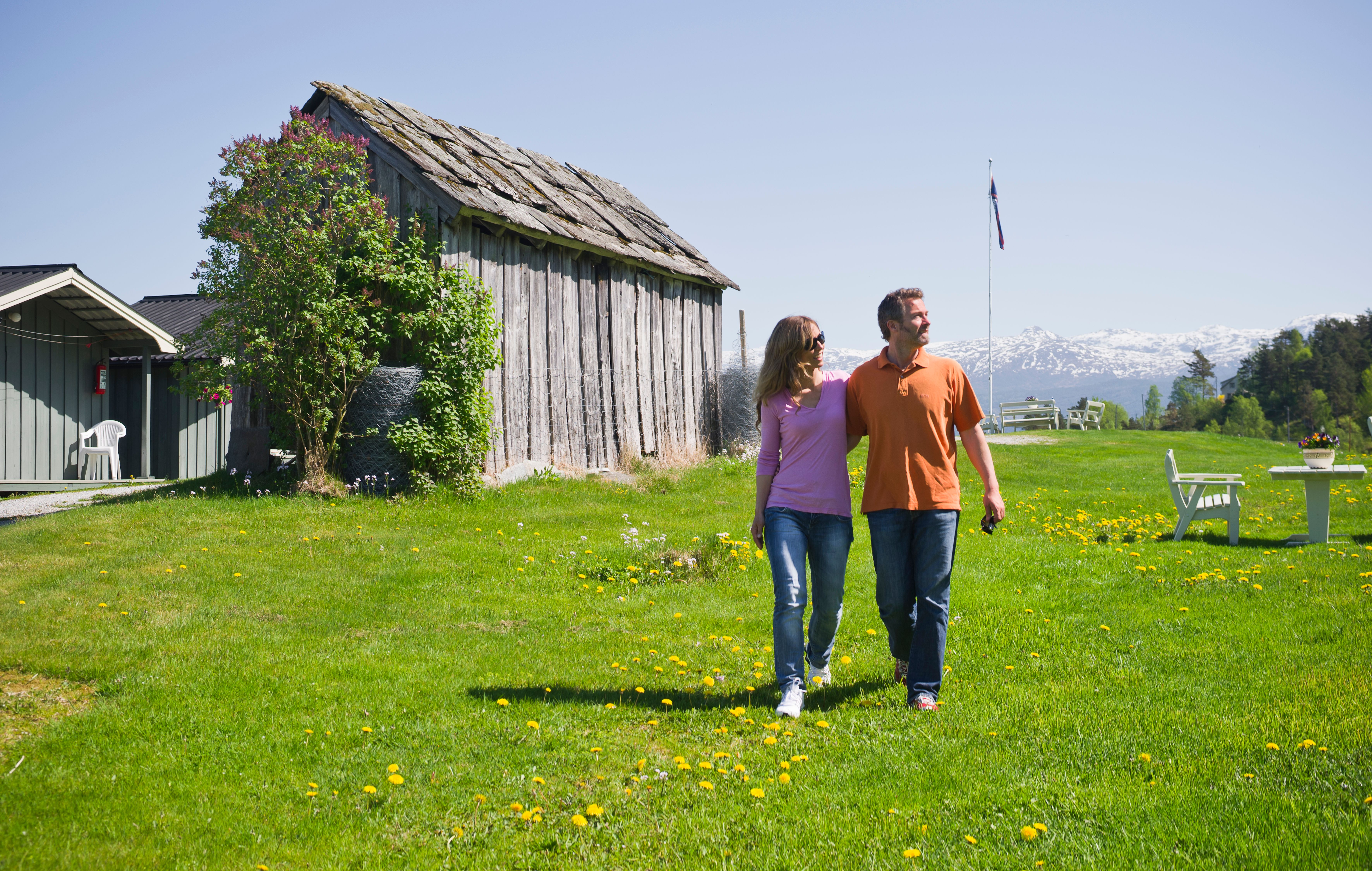 Couple walking among cabins and green lawns at Oddland Camping in Hardanger.