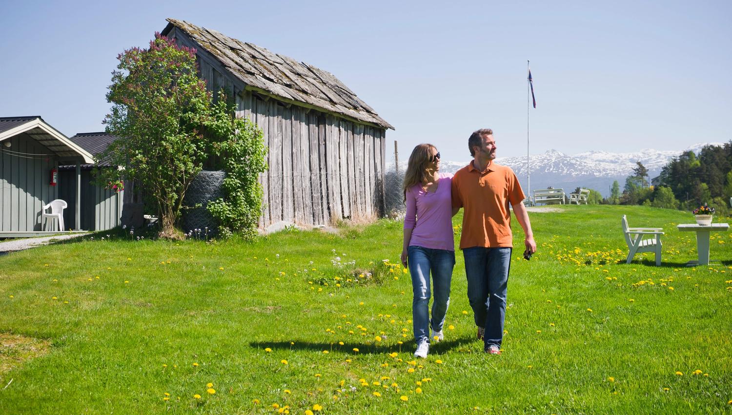 Couple walking among cabins and green lawns at Oddland Camping in Hardanger.