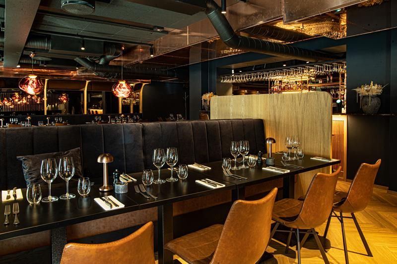 Black tables set for dining, black seating section and orange chairs