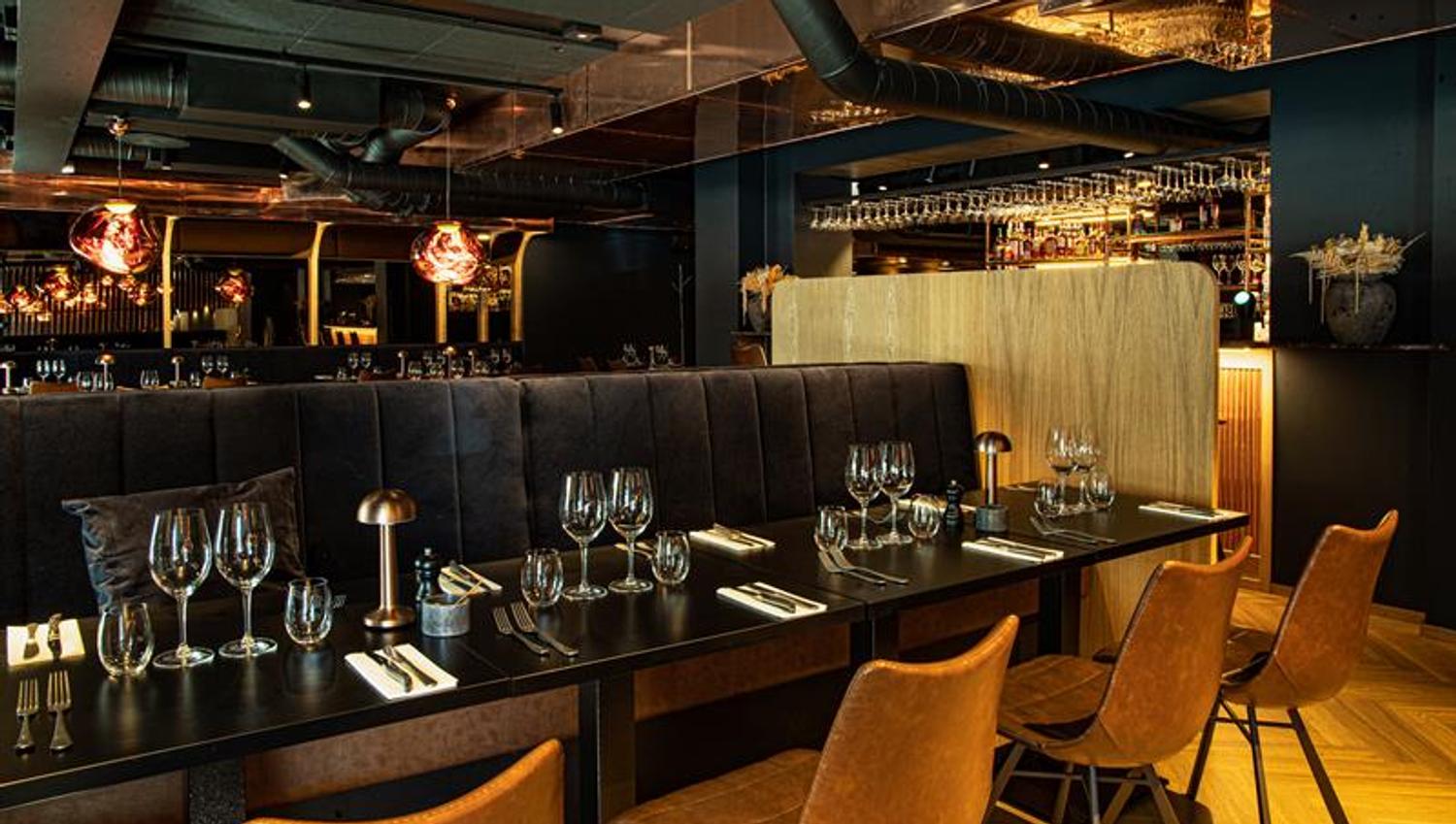Black tables set for dining, black seating section and orange chairs