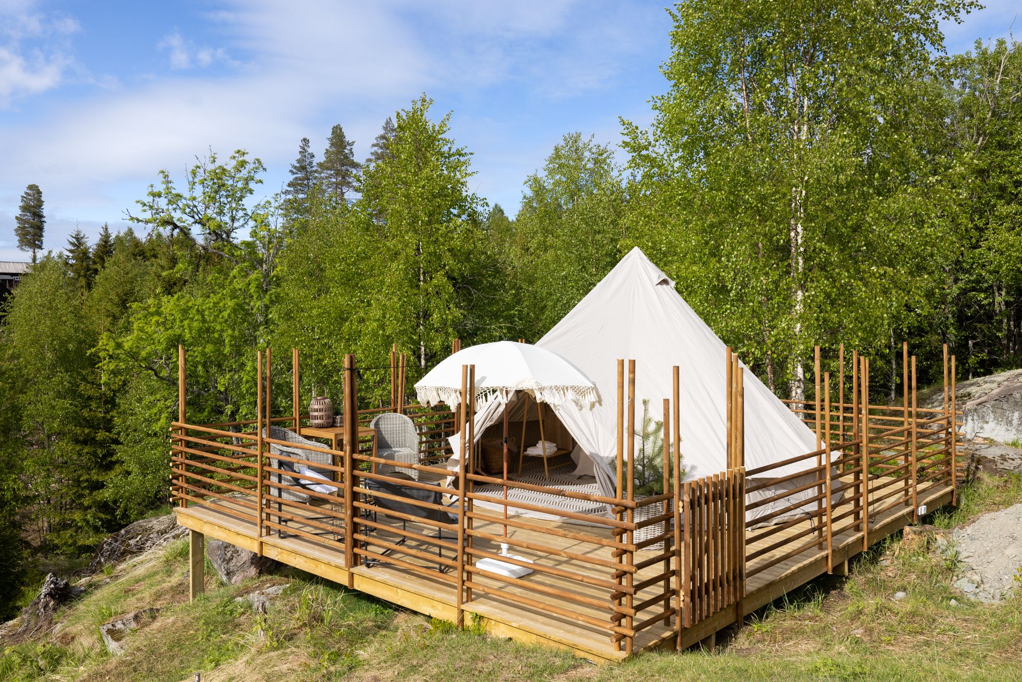 Wooden deck with the tent, parasol, chairs surrounded by a wooden fence, 
