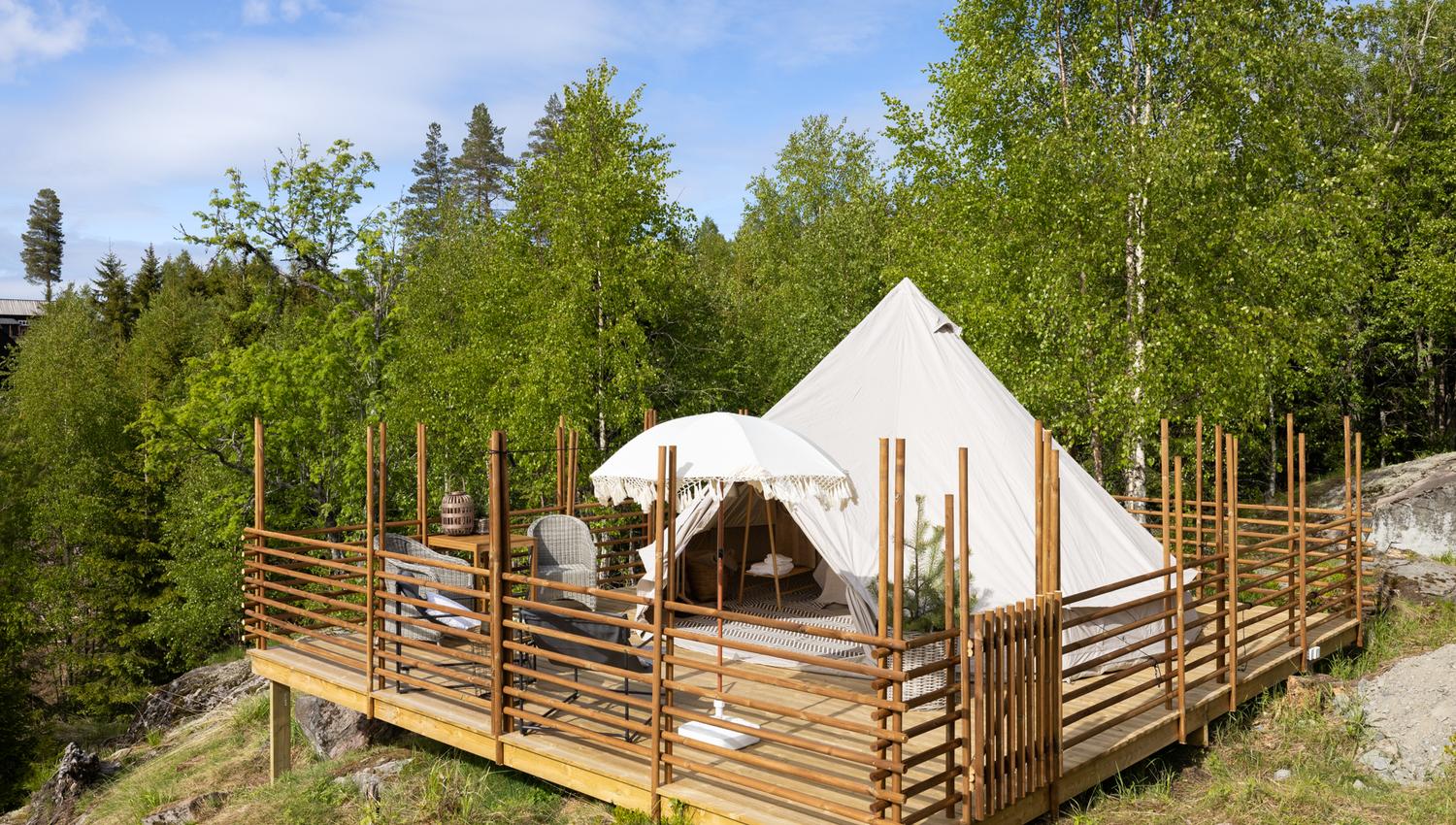 Wooden deck with the tent, parasol, chairs surrounded by a wooden fence,
