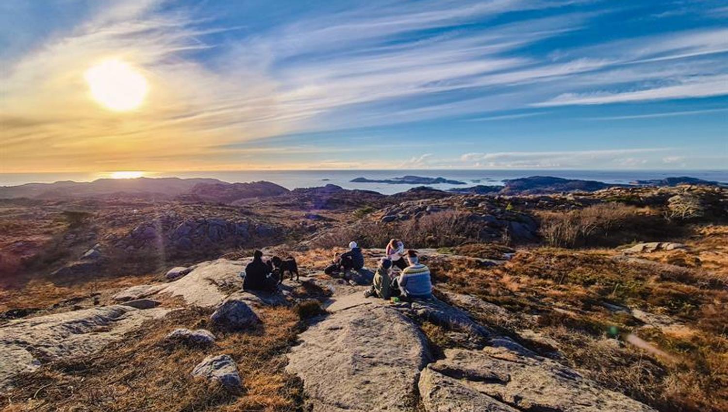 A group of people sitting on the rocks, overlooking the sea.