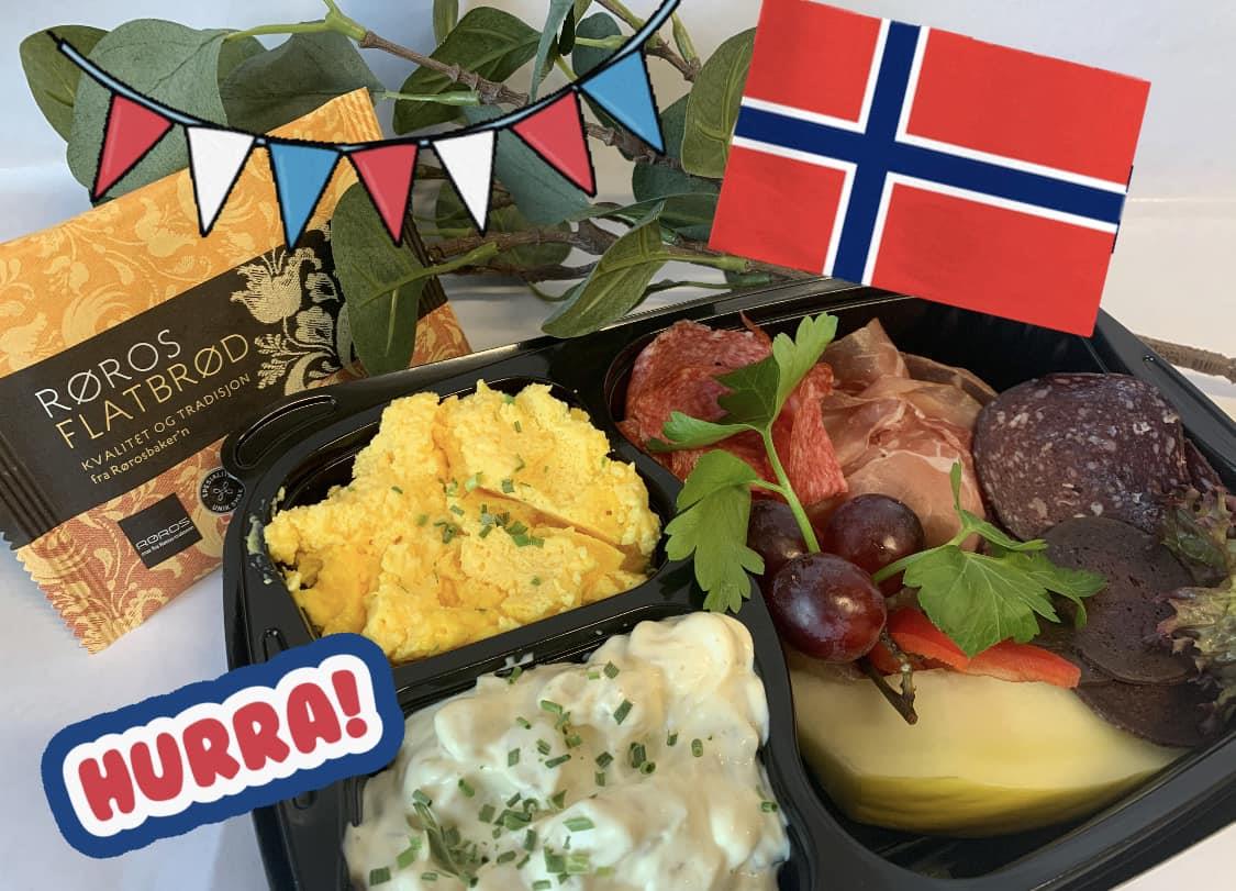 Et festpyntet matbrett med ost, kjøtt og salater, dekorert med norsk flagg og bunting.