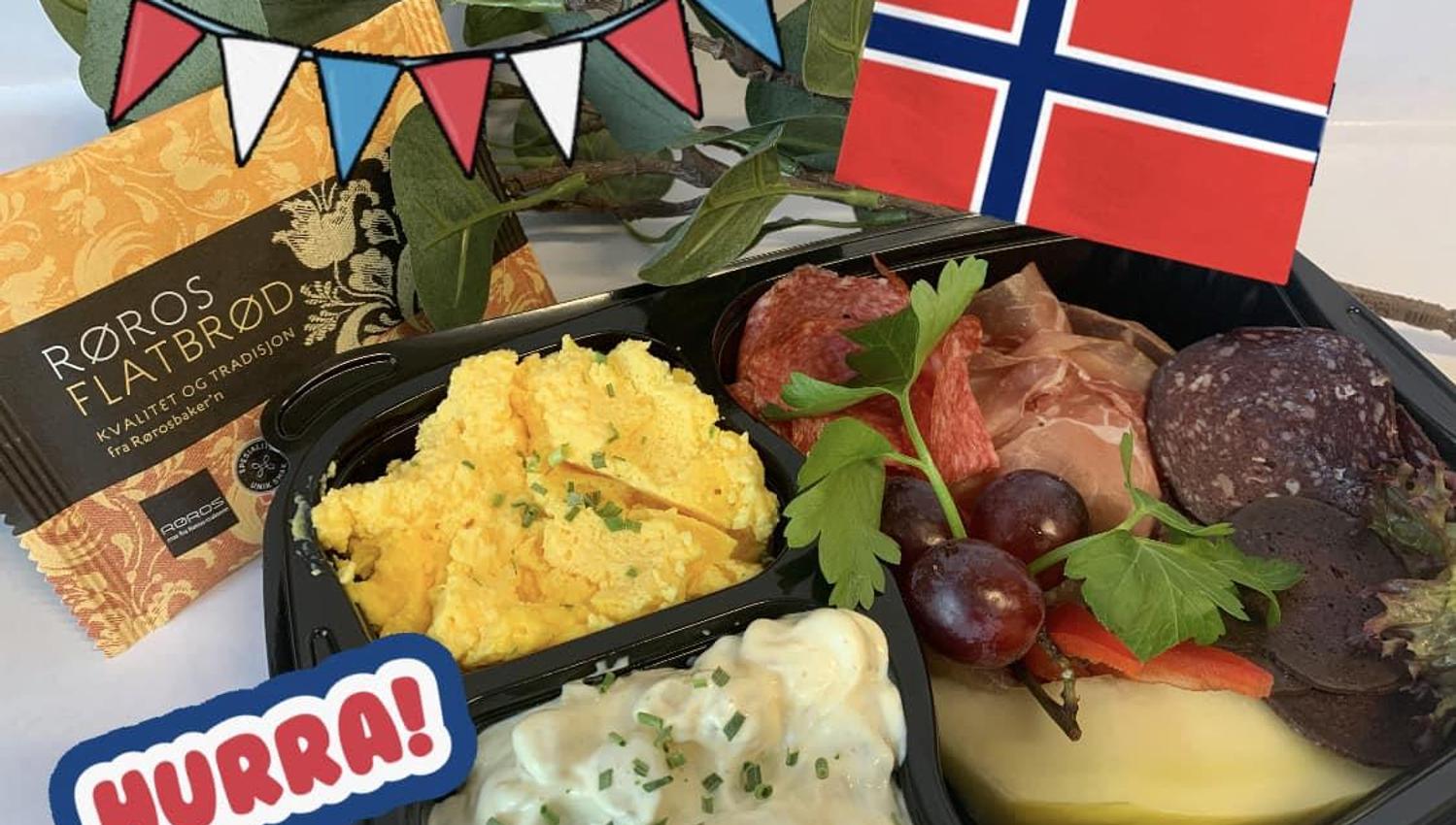 Et festpyntet matbrett med ost, kjøtt og salater, dekorert med norsk flagg og bunting.