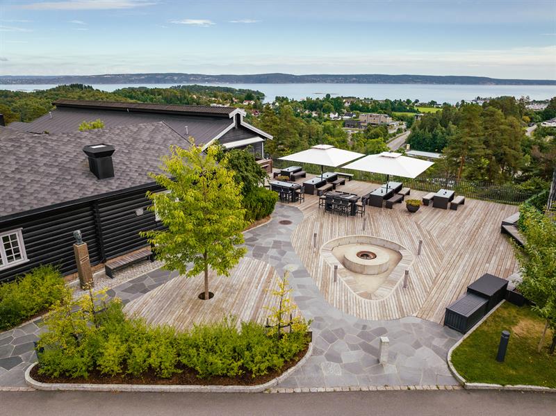 Terrassen på Leankollen, firepit, sittegrupper under parasoller og sjøutsikt over Oslofjorden
