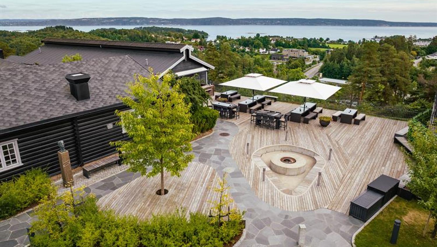 Terrassen på Leankollen, firepit, sittegrupper under parasoller og sjøutsikt over Oslofjorden