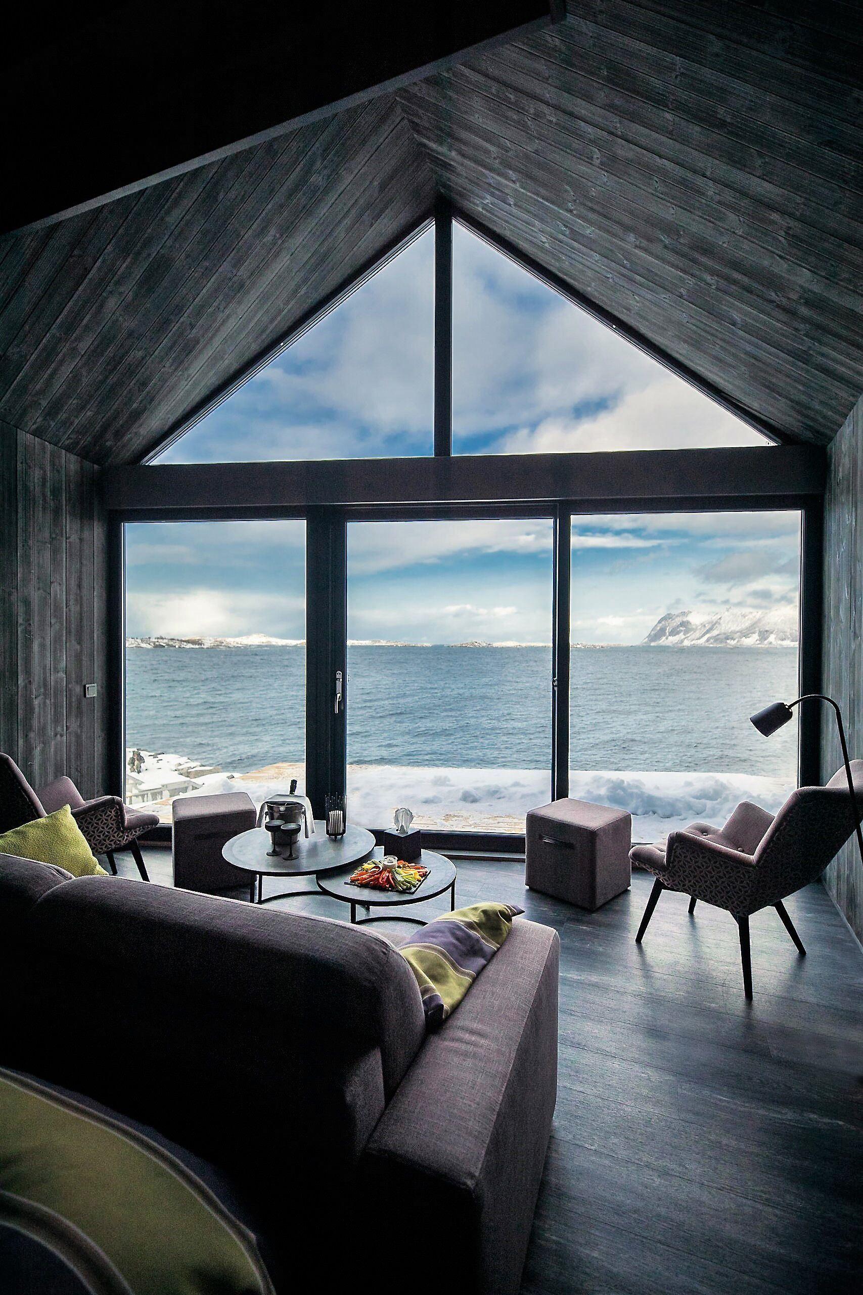 moderne stue med store vinduer som har fantastisk utsikt over fjord og fjell