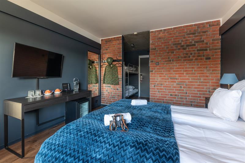 Hotel room with brick wall, tv and bed 