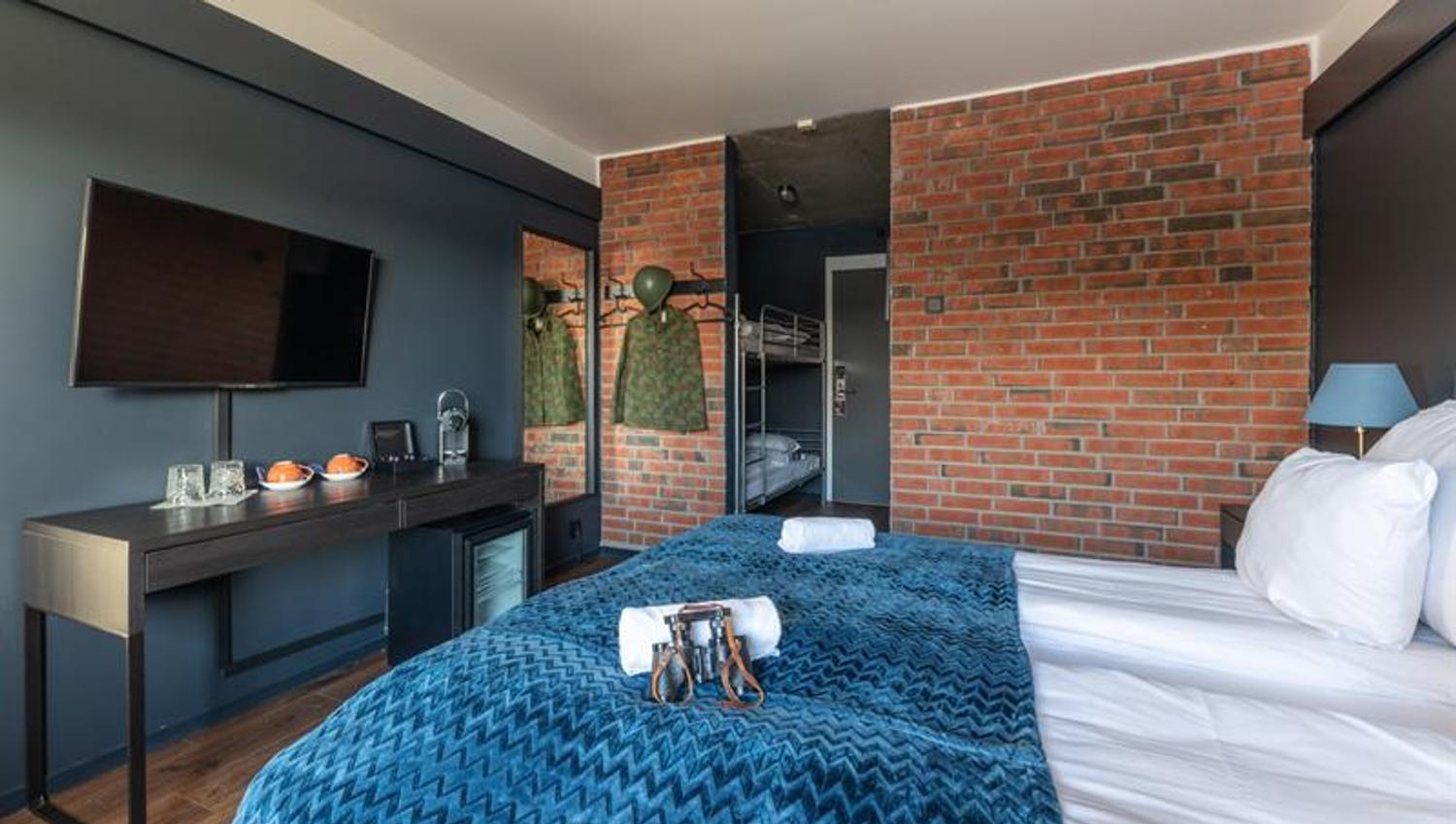 Hotel room with brick wall, tv and bed