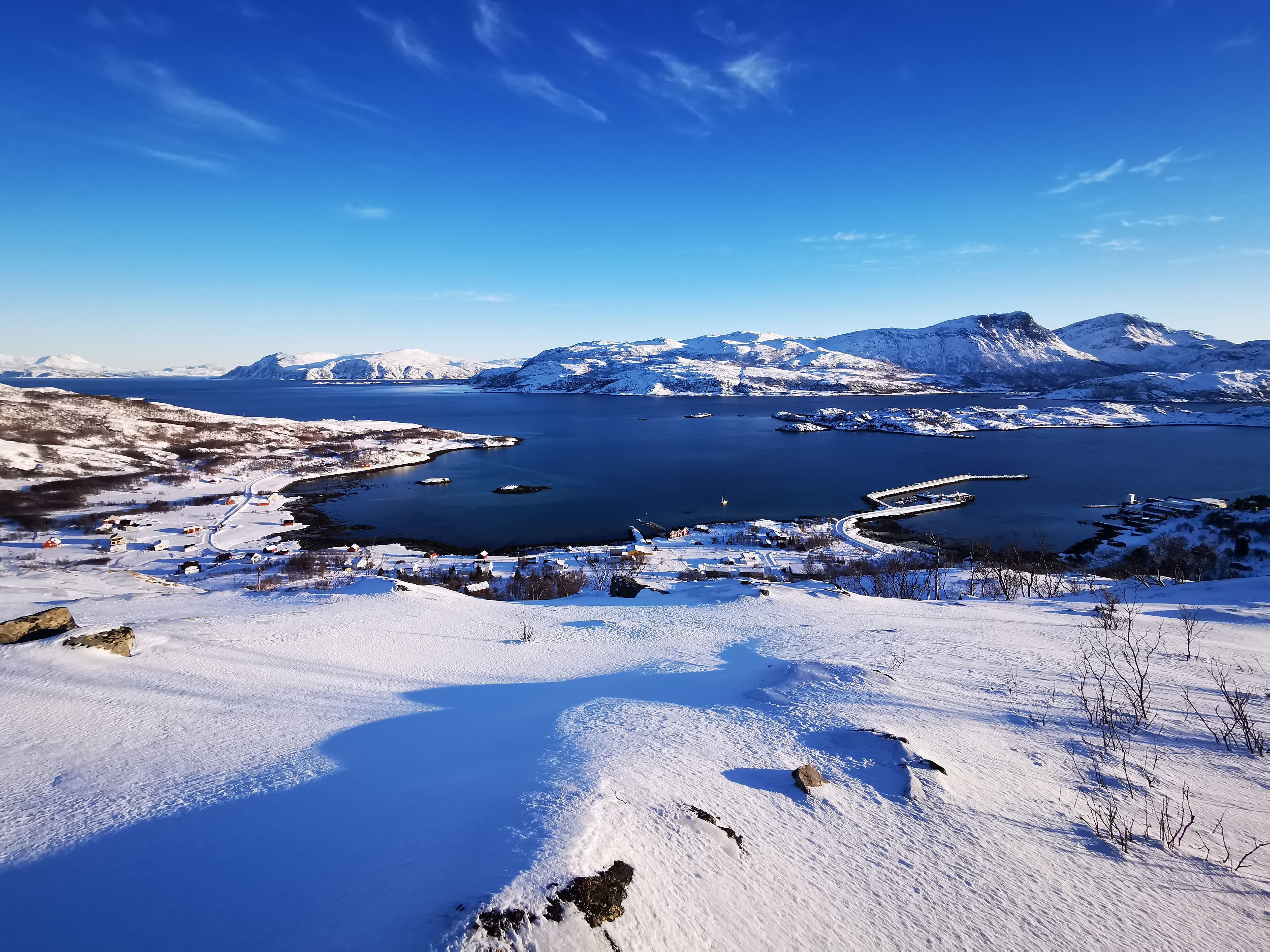Overview photo of the area of the cabins in winter with the fjord and mountains in front