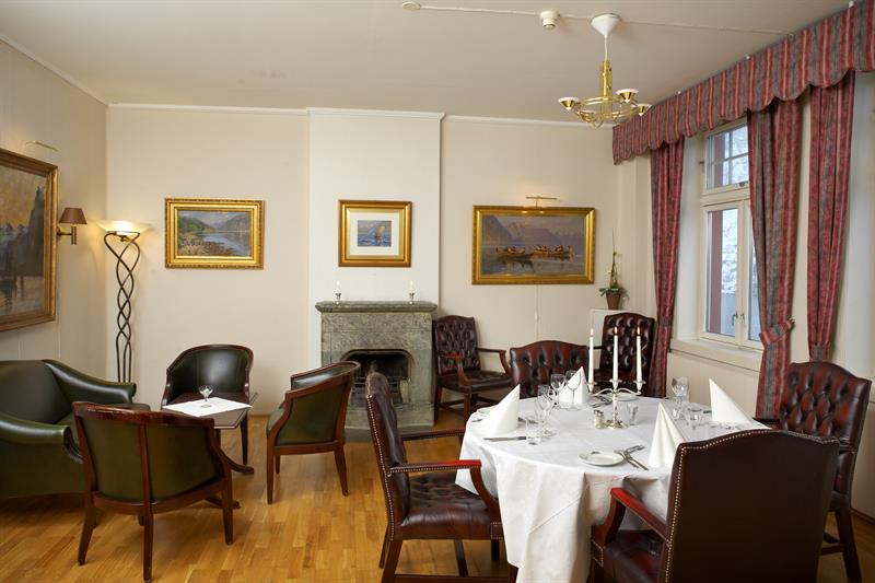 Elegant dining room with classic furniture, a fireplace, and an authentic atmosphere at Tyssedal Hotel.