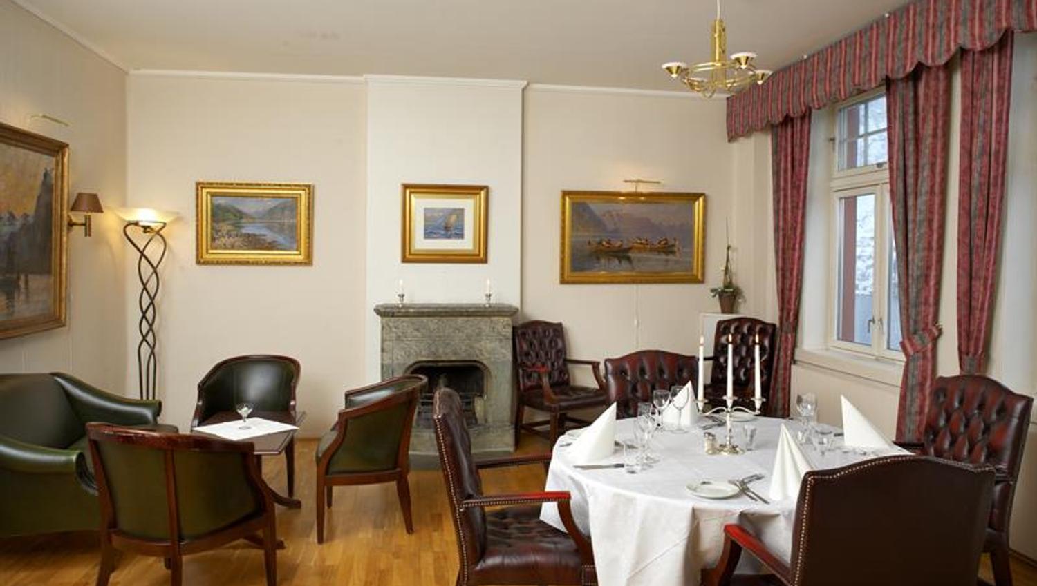 Elegant dining room with classic furniture, a fireplace, and an authentic atmosphere at Tyssedal Hotel.