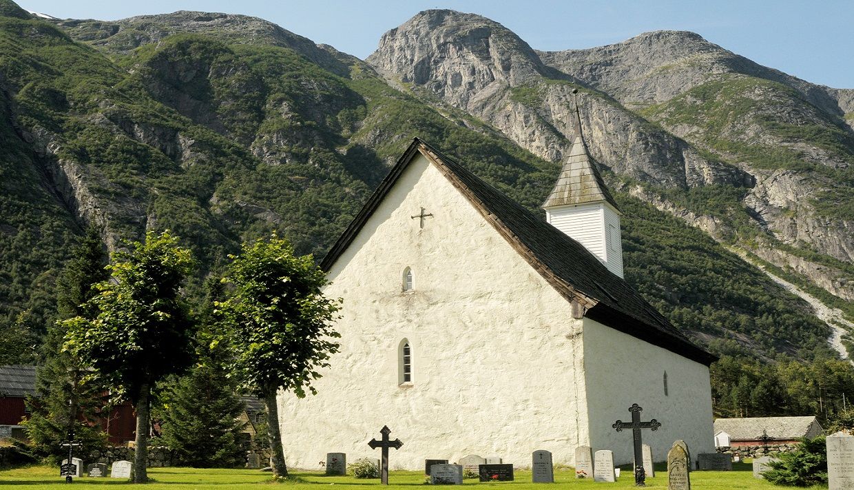 The church surrounded by greeneries. The old graveyard in the church garden in front.