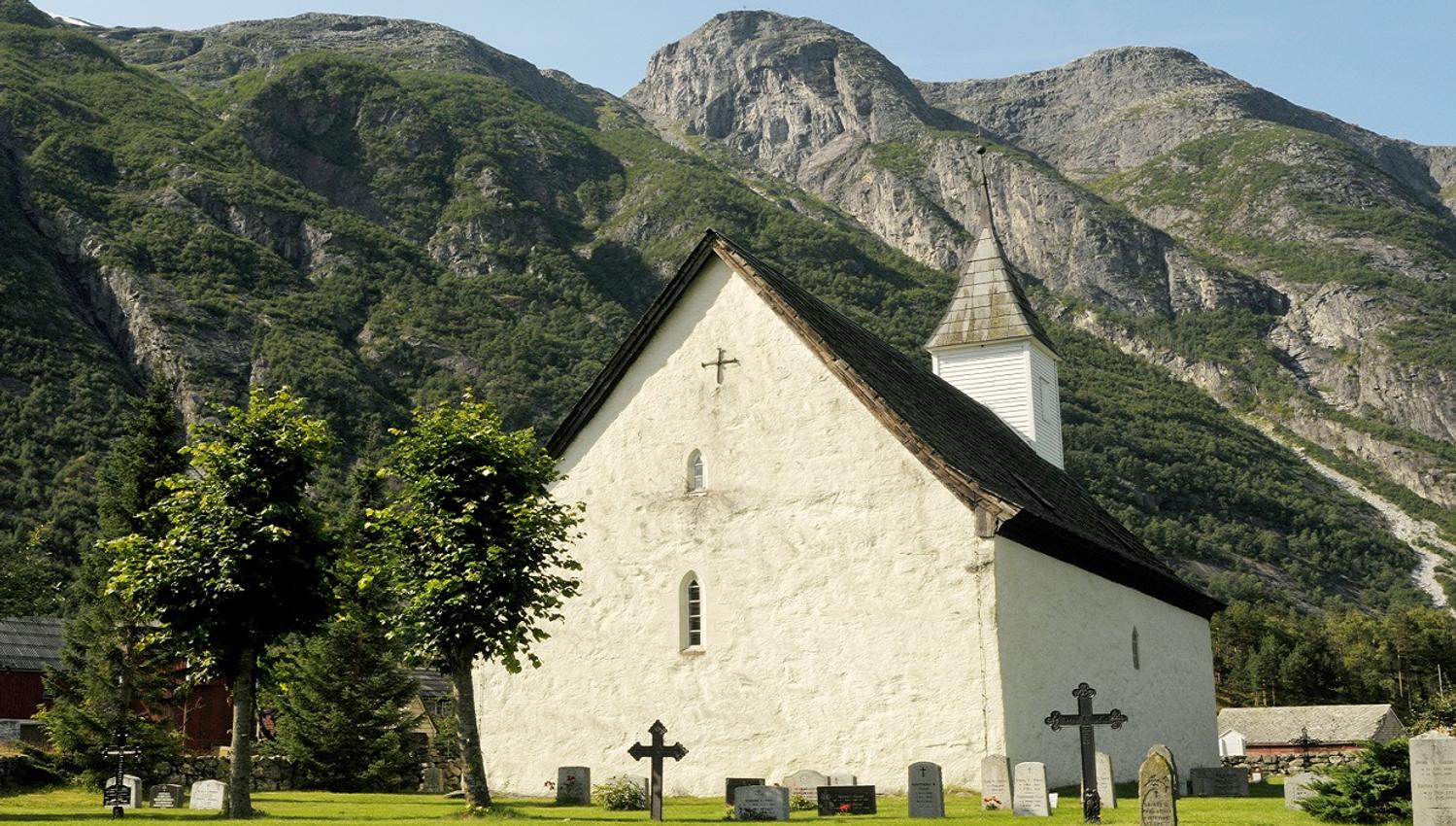 The church surrounded by greeneries. The old graveyard in the church garden in front.