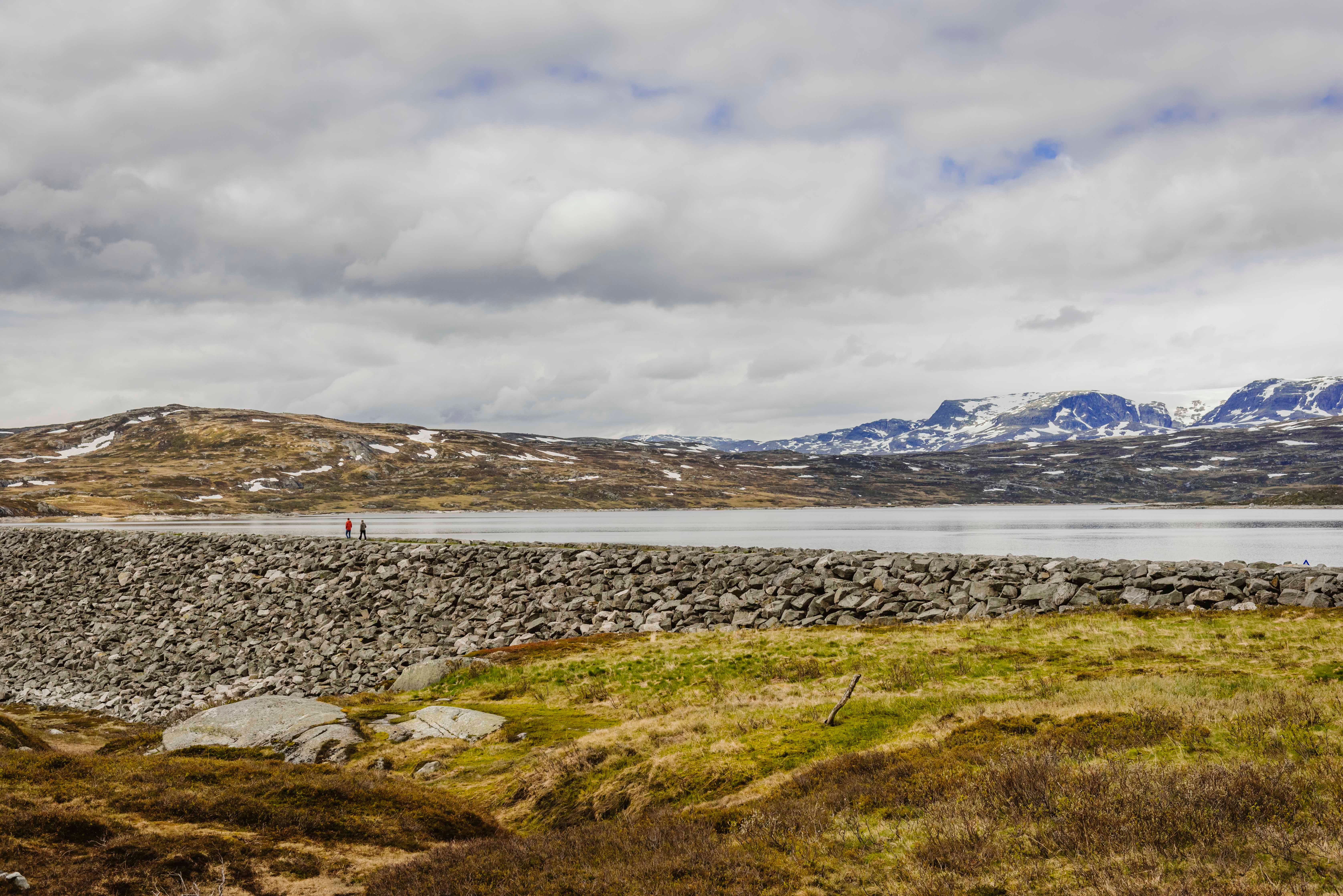 Two persons walking on top of the dam.