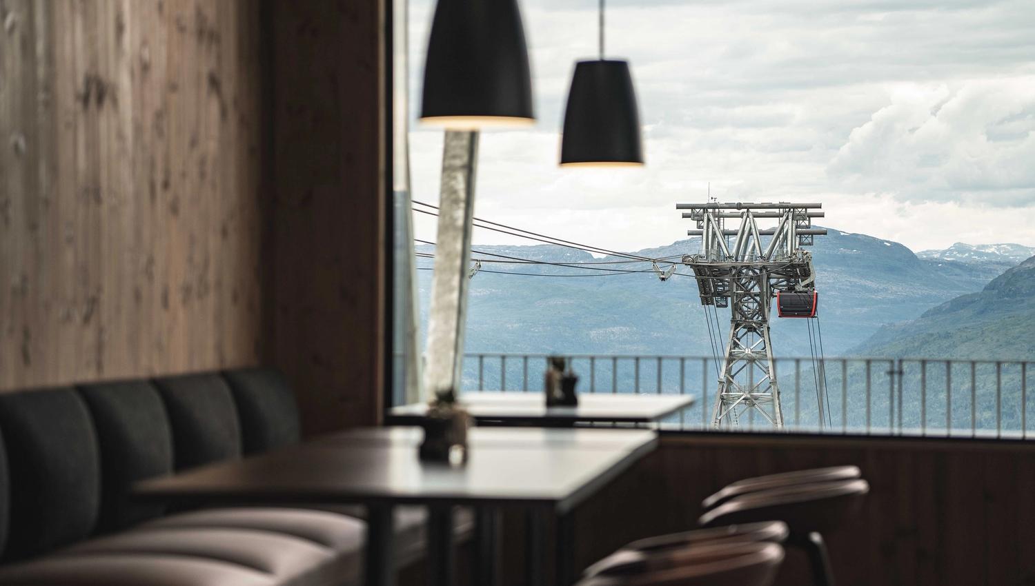 The inside of the restaurant at mount Hangur, with views of the gondola and the mountains.