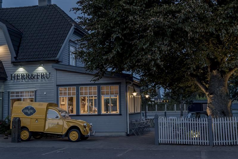 Facade at night: gray restaurant. Yellow delivery van parked at the restaurant.