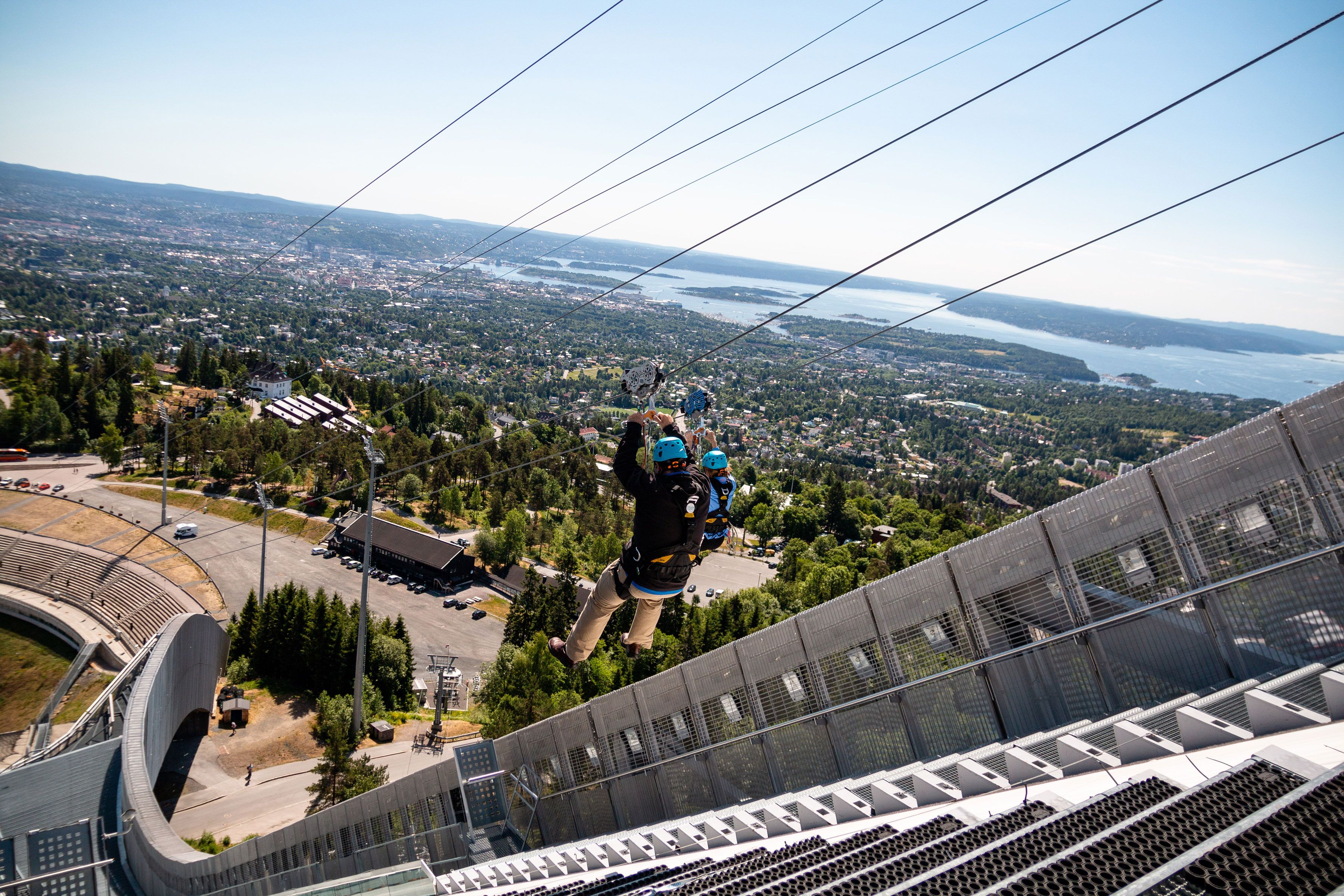 Two people ziplining down Holmenkollen Ski Jump.