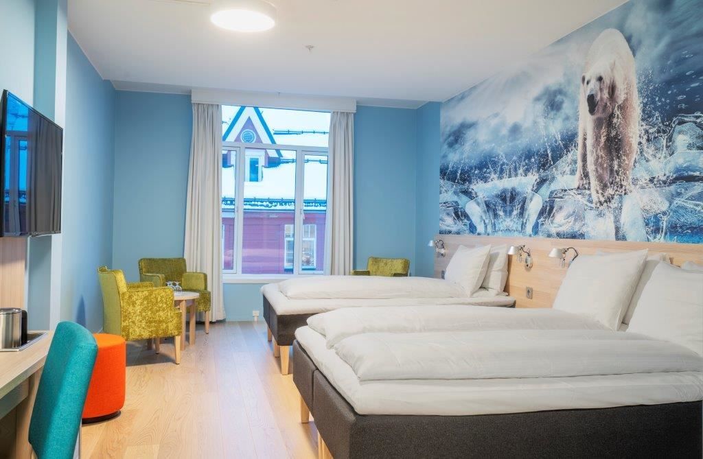 Modern hotel room with two single beds, polar bear mural on the wall, and a desk with a TV.