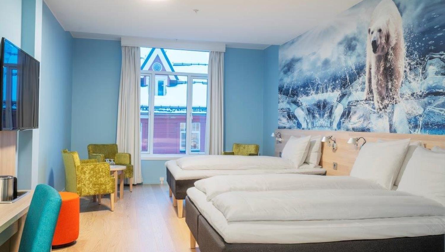 Modern hotel room with two single beds, polar bear mural on the wall, and a desk with a TV.