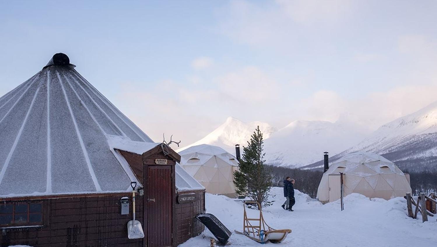 A lavvu and several tents in the snow in an Arctic setting