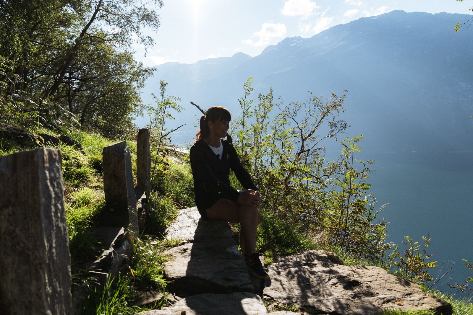 A woman sitting on a bench with the Hardangerfjord in the background. 