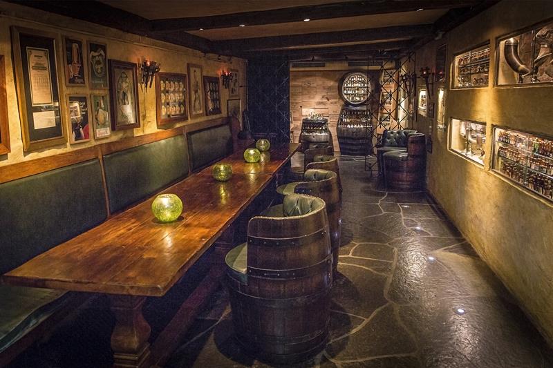 Seating section, long wooden table, chairs made from barrels and small bottles on display