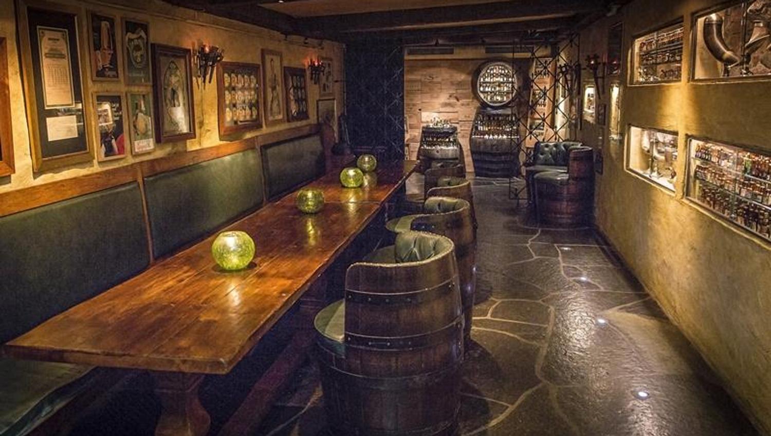 Seating section, long wooden table, chairs made from barrels and small bottles on display