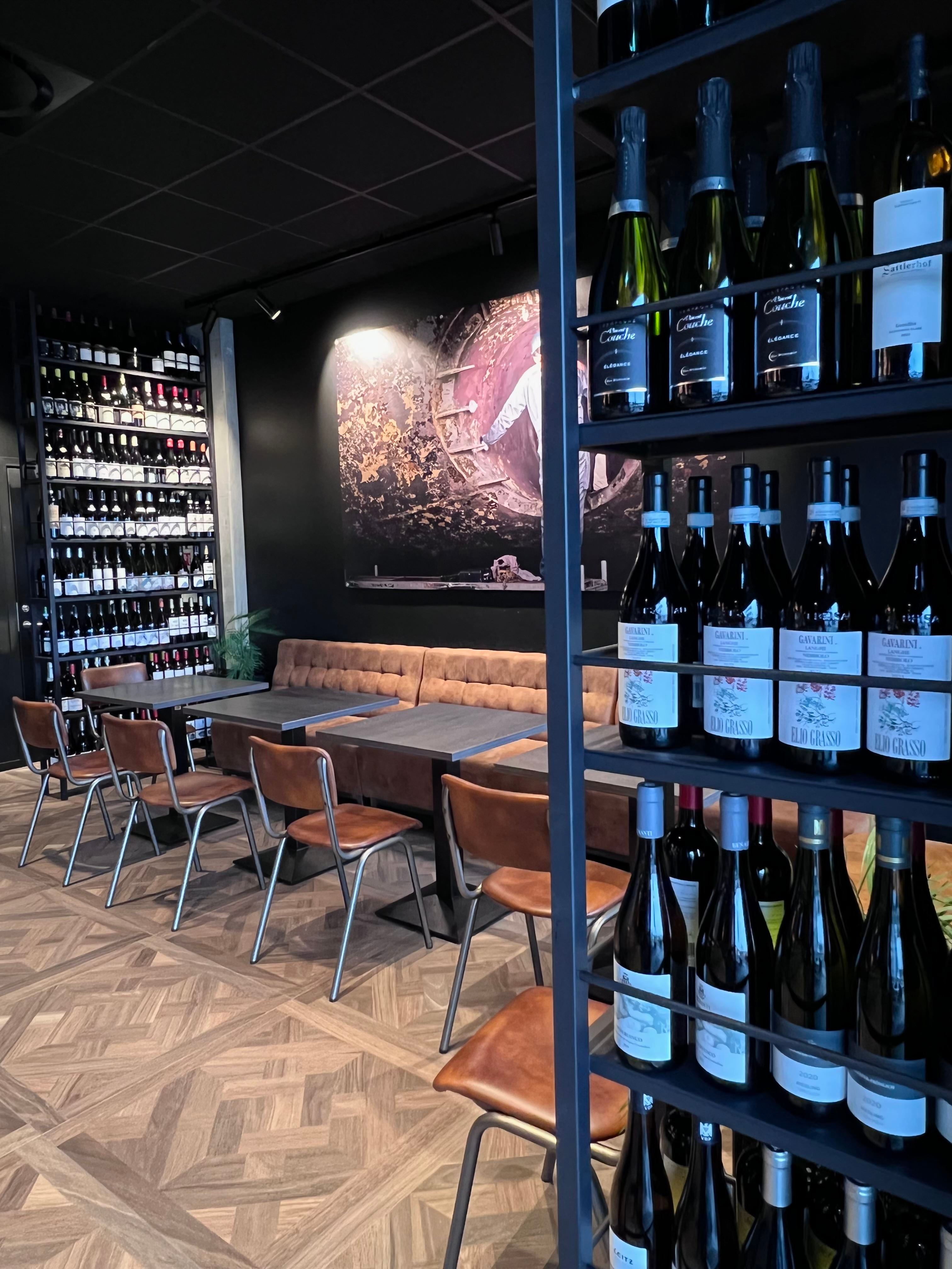 Sitteplasser ved baren, vinflasker rundt omkring i lokalet på hyller og langs veggen