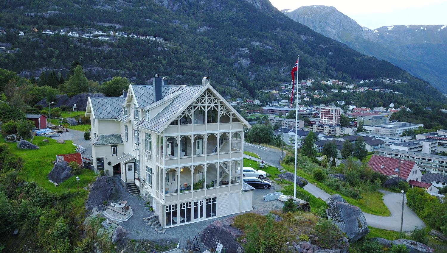 Vikinghaug Apartments overlooking Odda town, offering panoramic views of the fjord and steep mountain slopes in Hardanger.