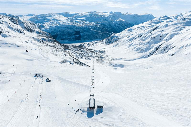 Blick vom Røldal Skigebiet hinunter auf den Fjord und das Dorf im Winterkleid.