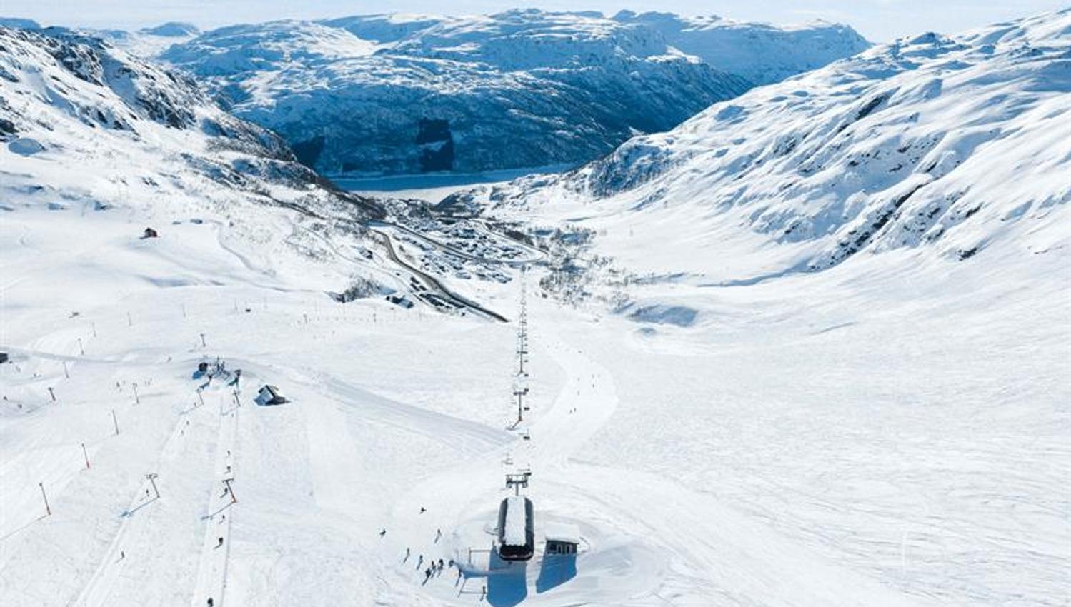 Blick vom Røldal Skigebiet hinunter auf den Fjord und das Dorf im Winterkleid.