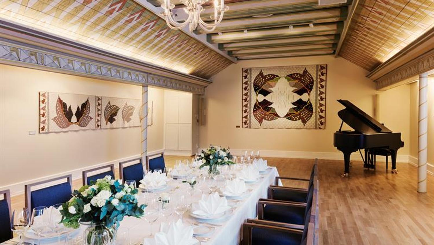 Long table set for dinner, grand piano in the background. Photo