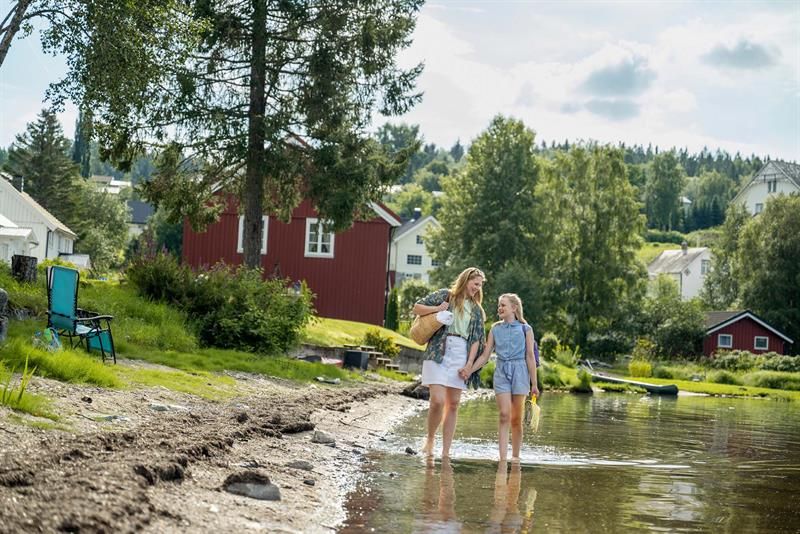 Mamma og jente vasser i vannkanten av Snåsavatnet  nedenfor Garveriet i Viosen