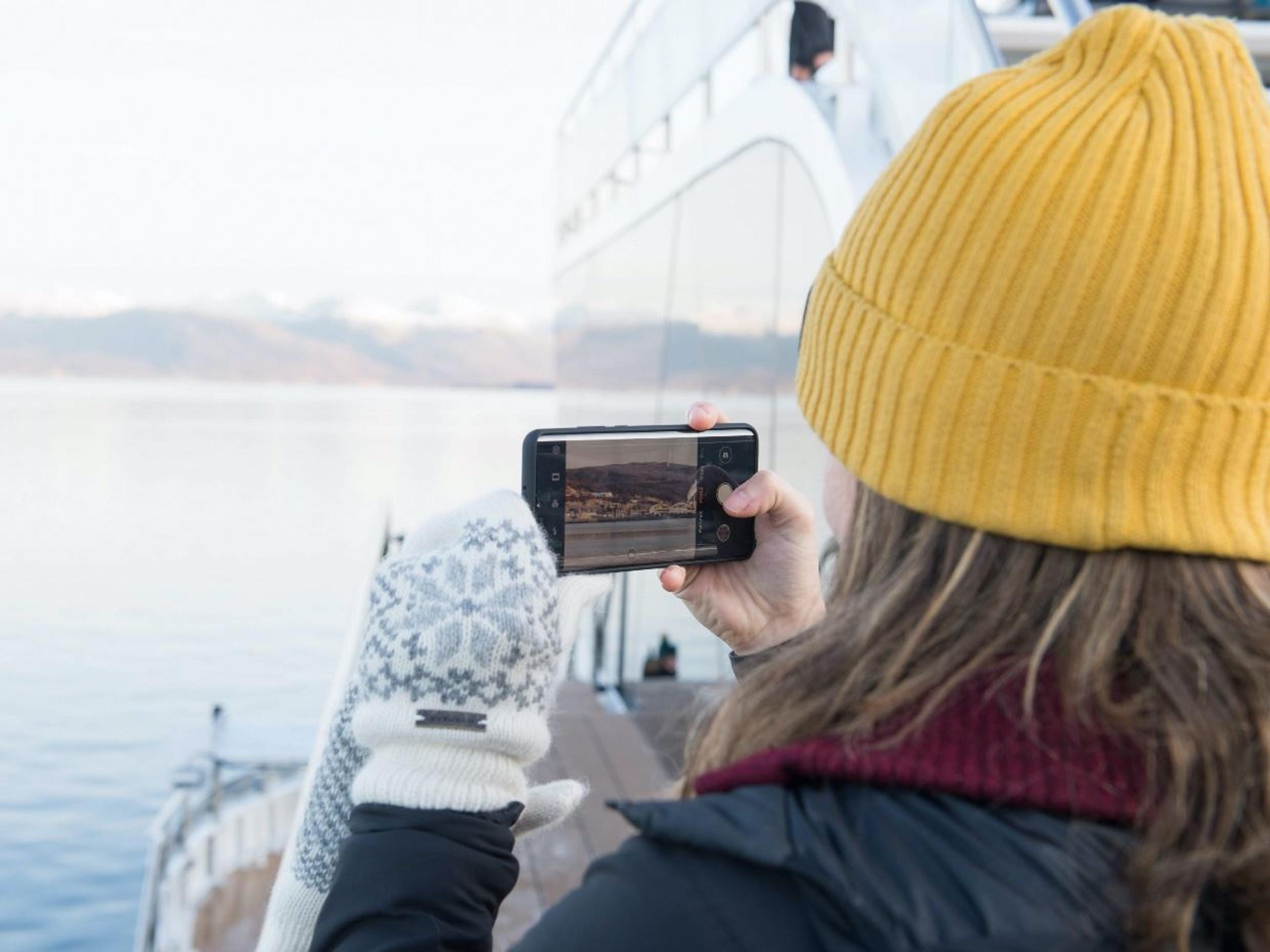 Guest photographing the fjord landscape from the vessel