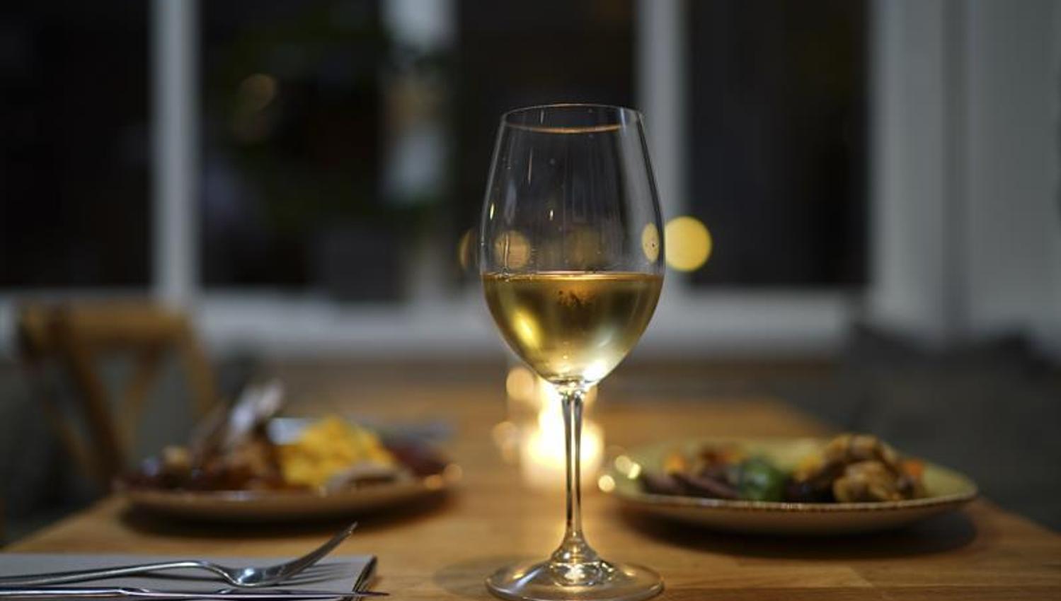 Wine in a glass and food on a plate.