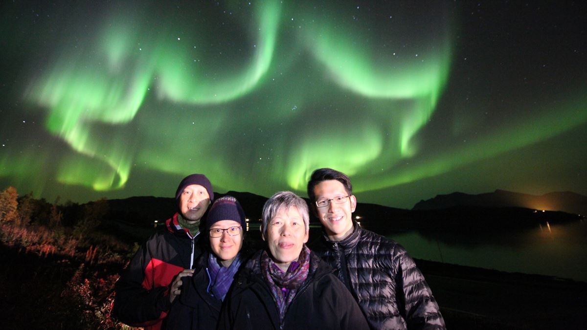 A group of guests standing under the northern lights