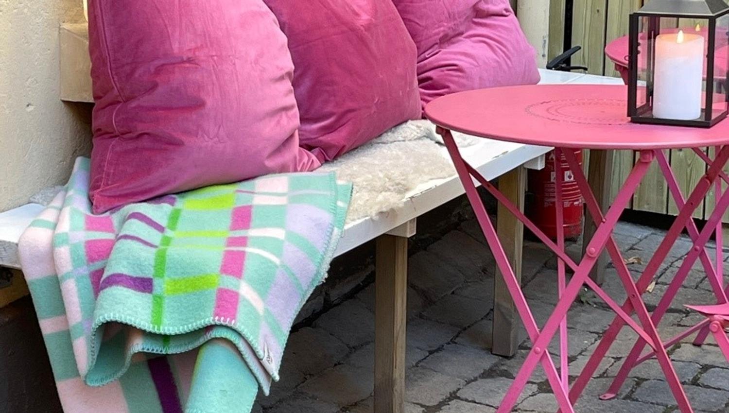Bench with pink table, pink cushions and blanket