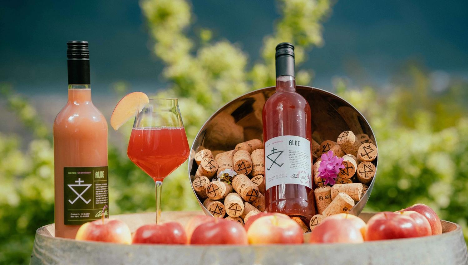Bottle and glass of Alde cider surrounded by apples and corks in Hardanger.