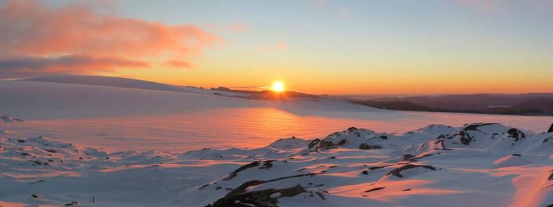 Magical sunset over Holmaskjer and the Folgefonna glacier, with soft pink light reflecting across the snow-covered high mountain plateau.