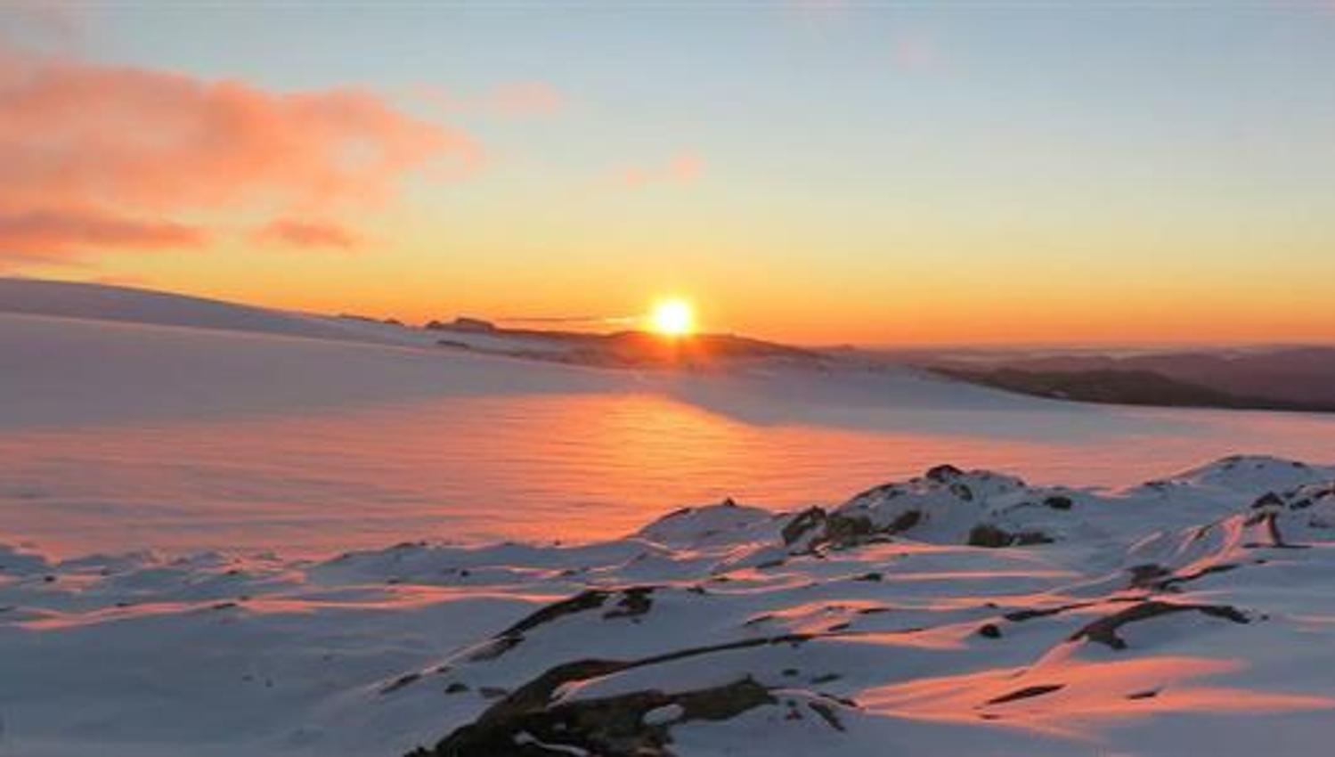 Magical sunset over Holmaskjer and the Folgefonna glacier, with soft pink light reflecting across the snow-covered high mountain plateau.