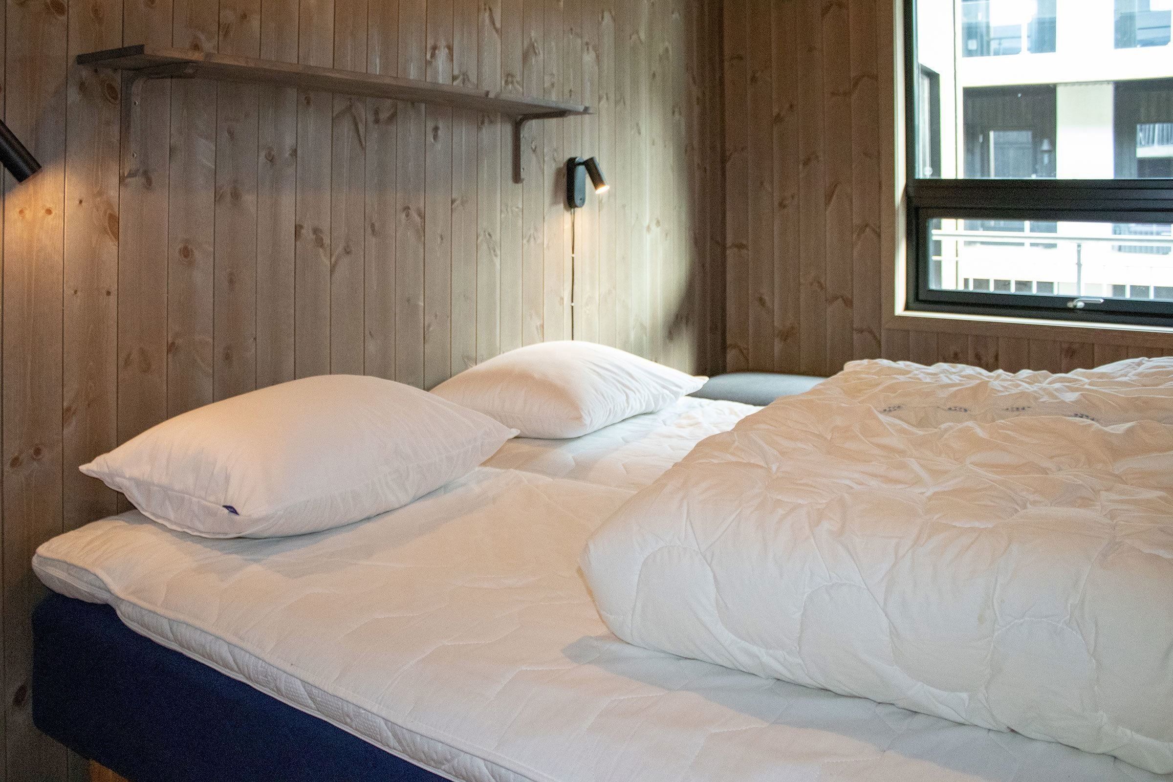 Ein Bett mit Kissen und einer Lampe in einem Zimmer.